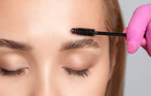 Makeup artist combs and plucks eyebrows after dyeing in a beauty salon.